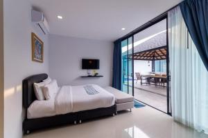 a bedroom with a bed and a sliding glass door at Lespalm Resort by Vacayandco in Ban Thalat Choeng Thale