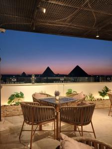 a patio with a table and chairs and a view of pyramids at Makan Pyramids View in Cairo