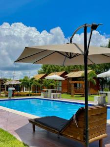 a bench with an umbrella next to a swimming pool at Pousada La Belle de Jour in Majorlândia