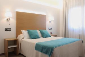 a bedroom with a large bed with blue pillows at Hotel La Noyesa *** Superior in O Grove