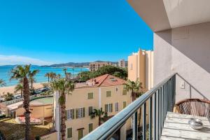 a balcony with a view of a building and the ocean at Anglade Hotel in Le Lavandou
