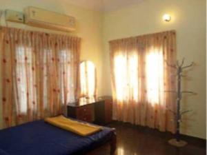 a bedroom with a bed and two windows with curtains at Dream Stay in Varkala +4 photos