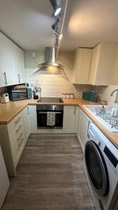 a kitchen with white cabinets and a stove and a washer at No 4 Devon Square in Kingsbridge