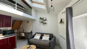 a living room with a chair and a kitchen at LE BORA - Duplex en Centre-ville - Puy-du-fouu in Cholet