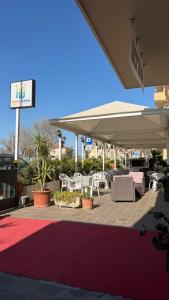 a patio with white chairs and tables and a sign at Hotel Gattei in Rimini +23 photos