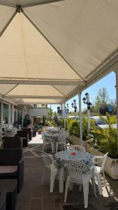 a patio with tables and chairs under a white umbrella at Hotel Gattei in Rimini