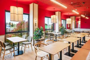 a restaurant with tables and chairs and red walls at B&B HOTEL Miranda de Ebro in Rivabellosa
