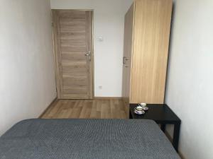 a bedroom with a bed and a table with a door at Inżynierska R1 in Wrocław
