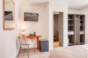 a bedroom with a desk and a chair and a bed at Anglade Hotel in Le Lavandou