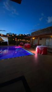 a swimming pool at night with two tables and a building at Recanto das Palmeiras hidro in Hidrolândia