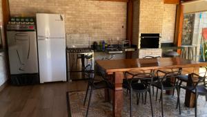 a kitchen with a wooden table and a refrigerator at Recanto das Palmeiras hidro in Hidrolândia