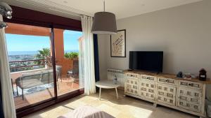 a bedroom with a tv on a dresser and a balcony at Alta Luminara Boutique Residence Sea View Terraces Marbella Hills in Benahavís