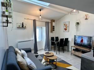 a living room with a blue couch and a tv at LE BORA - Duplex en Centre-ville - Puy-du-fouu in Cholet