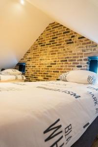 two beds in a room with a brick wall at De Moolt Vakantiewoningen in Eckelrade