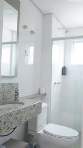 a white bathroom with a toilet and a sink at Nostro Hotel in Pato Branco +38 photos