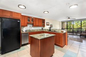 a kitchen with wooden cabinets and a black refrigerator at Kona Pacific C317 in Kailua-Kona