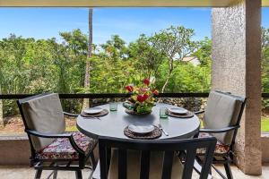 a table with chairs and a vase of flowers on a porch at Kona Pacific C317 in Kailua-Kona