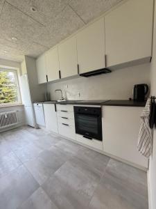 a kitchen with white cabinets and a black appliance at Completely renovated apartment, 6 sleeps in Herning