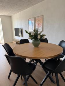 a table with chairs and a vase of flowers on it at Completely renovated apartment, 6 sleeps in Herning