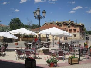 a group of tables and chairs with white umbrellas at Hostal Rural Jarpar in Grajera
