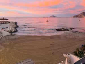 a beach at sunset with a boat in the water at Ti Miquel in Ifach