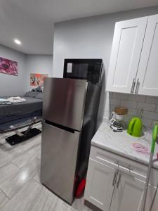 a kitchen with a stainless steel refrigerator and a bed at Newly built Studio in Irvington