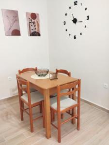 a dining room table with chairs and a clock on the wall at Maria's Sweet Home in Chios