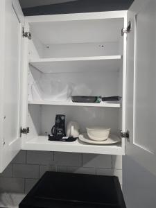 a white cabinet with a plate and dishes in it at Newly built Studio in Irvington +20 photos