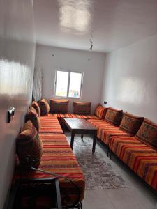a room with long couches and tables in a room at Yousef appartement in Taghazout
