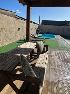 a wooden bench sitting on a deck next to a pool at Casa com piscina aquecida e quadra de vôlei in Osório