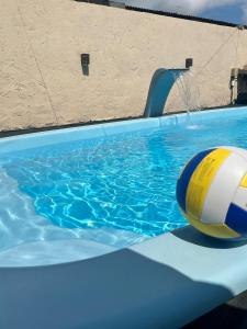 a swimming pool with a ball in the water at Casa com piscina aquecida e quadra de vôlei in Osório