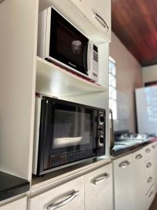 a kitchen with a microwave oven and a stove at Casa com piscina aquecida e quadra de vôlei in Osório