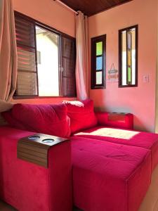 a red couch sitting in a room with windows at Casa com piscina aquecida e quadra de vôlei in Osório +18 photos