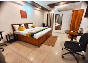 a bedroom with a bed and a desk and chairs at Hotel Blueberry in New Delhi