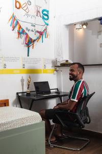 a man sitting in a chair in front of a desk at Books Hostel in Rio de Janeiro