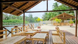 a restaurant with wooden tables and chairs next to the water at L'île de Marie-Jo in Assinie