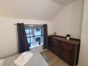 a bedroom with a bed and a window with a dresser at FLAT 2 Seven Cambrian Square First Floor Flat in Newtown