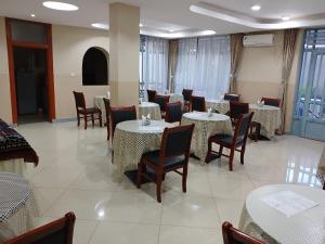 a dining room with tables and chairs and windows at Gosen Hotel Lubumbashi in Lubumbashi