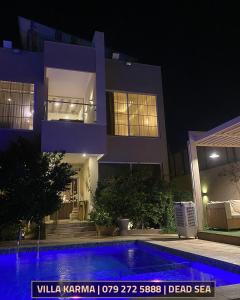 a house at night with a swimming pool in front of it at Villa karma in Al Rama