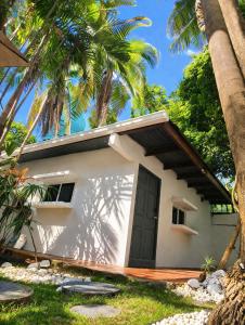 a small white building with a door and palm trees at CulturaHumana Guesthouse in Panama City