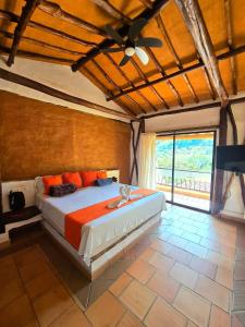 a bedroom with a large bed with orange pillows at Cabañas el Nopal in San Gil +52 photos