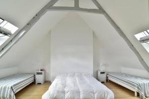 two beds in a bedroom with white walls and windows at La tourelle du Val-d'Arguenon in Pluduno