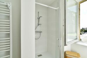 a shower in a white bathroom with a window at La tourelle du Val-d'Arguenon in Pluduno