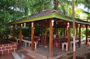 a wooden gazebo with tables and chairs at Nisarg Resort in Guhagar