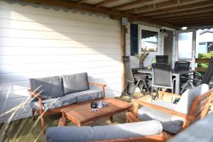 a patio with a couch and a table and chairs at Northseachalets Ameland in Buren +14 photos