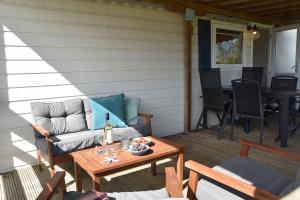 a patio with a couch and a table on a porch at Northseachalets Ameland in Buren