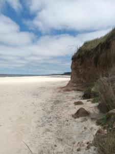 a sandy beach next to a cliff with a cloudy sky at Calma Home in San Luis
