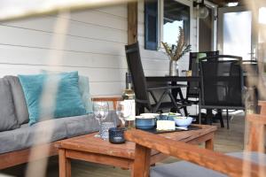 a patio with a couch and a table with wine glasses at Northseachalets Ameland in Buren