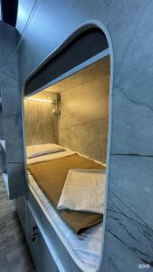 a small bed in a room with a mirror at Arch Hostel in Almaty +16 photos