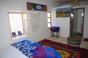 a bedroom with a bed and a chair and windows at Chez youba in Azilal